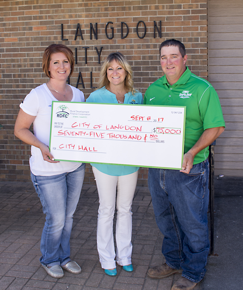 Photo Caption: Kristen Gendron (left), United Communications, and Marty Tetrault (right), Cavalier Electric Cooperative, present a loan check to Langdon City Auditor Roxanne Hoffarth (center). 